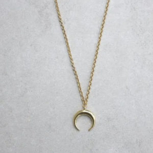 This crescent moon necklace is part of the Talisman Alchemy collection (long, level three length), gold-plated, and worn with a 36” gold-finished steel curb chain. Completed with a lobster claw clasp and chain end. Stone approximately 3/4 inch; will vary in size. Necklaces within the Talisman Alchemy section are designed to be easily layered with a second and third piece for a completed look that is both beautifully unique and magical. The crescent moon (or lunula in ancient Roman culture) is an iconic shape that calls upon the spirit of the goddess for energy and feminine powers. Traditionally worn by Roman girls, the crescent moon was utilized as protection against evil forces, demons, and sorcery.